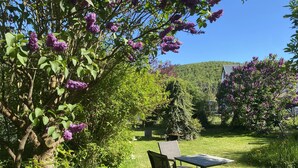 Un jardin avec une table et des chaises, entouré d’arbres et d’arbustes.