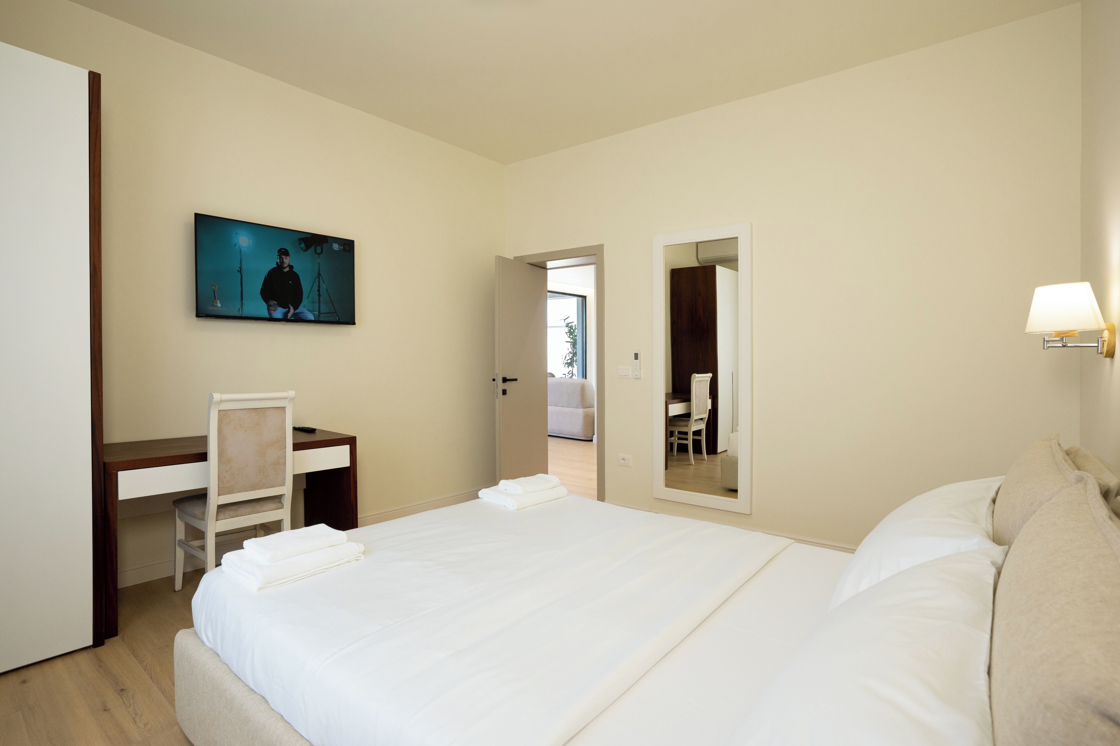 Une chambre d’hôtel avec un lit, un bureau, une chaise, une télévision et un miroir.
