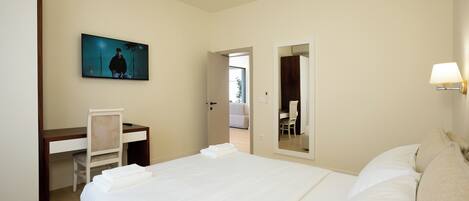 Une chambre d’hôtel avec un lit, un bureau, une chaise, une télévision et un miroir.