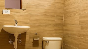 Un baño con lavamanos, inodoro y cubo de basura.