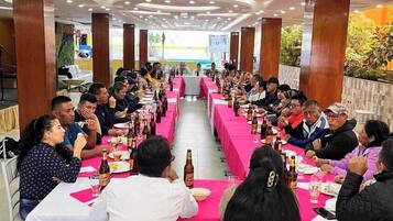 A conference room with long tables, white chairs, and a stage at the front.