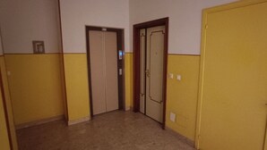 A hallway with two doors, one with a light switch and another with a door handle.