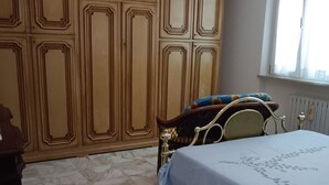 A bedroom with a bed, a chandelier, a wardrobe, and a window.