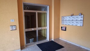 A hotel entrance with a glass door, a mail drop, and a wall-mounted mailboxes.