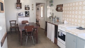 Une cuisine compacte comprenant une table à manger, des chaises, une cuisinière et un petit réfrigérateur.