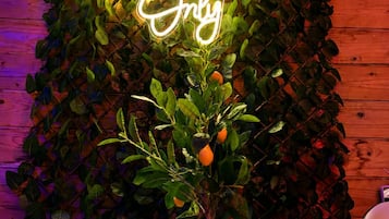 Neonbord met de tekst 'Good Vibes Only' boven een plant in een houten kamer.