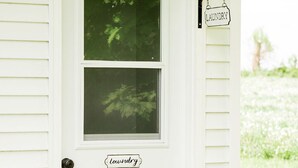 A white house with a front door labeled "laundry" and a small window above it. - Gallant Cottage-PEI Charm, updated cottage with AC near Charlottetown. Waterview (Alexandra)