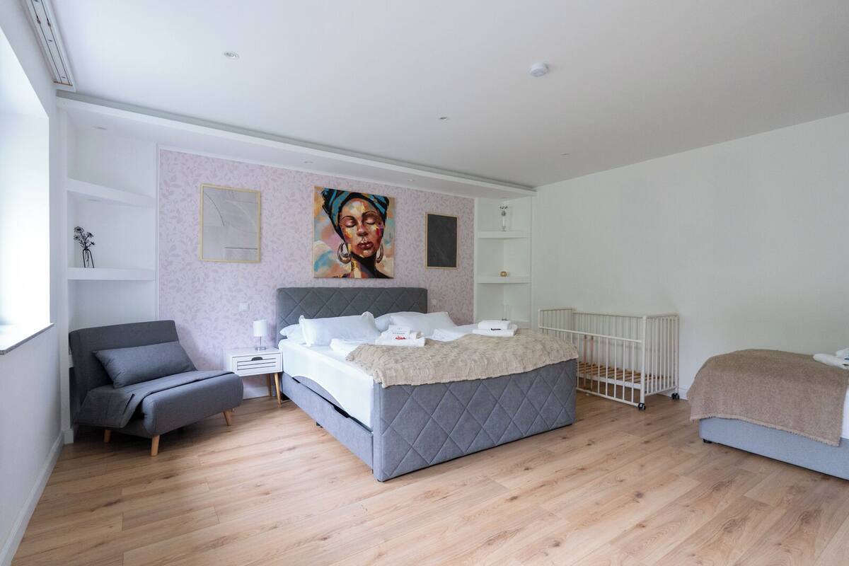 Ein modernes Schlafzimmer mit Bett, Stuhl, Heizkörper und Bildern an den Wänden.