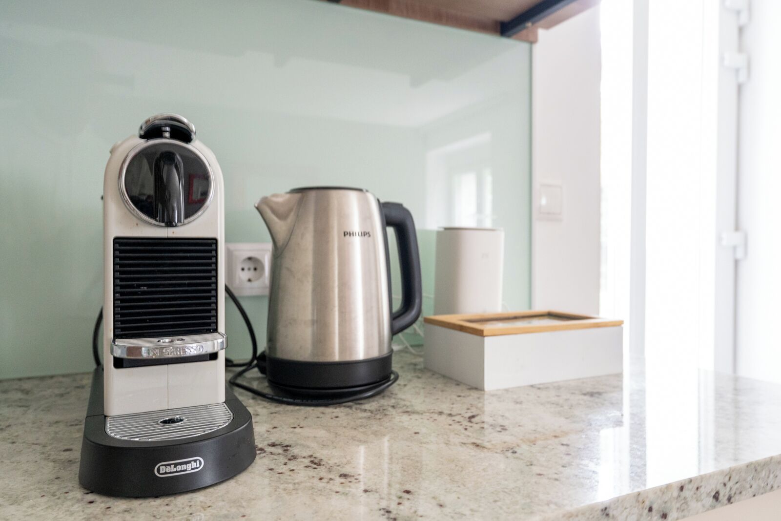 A kitchen with a coffee maker, kettle, and a box on the counter.
