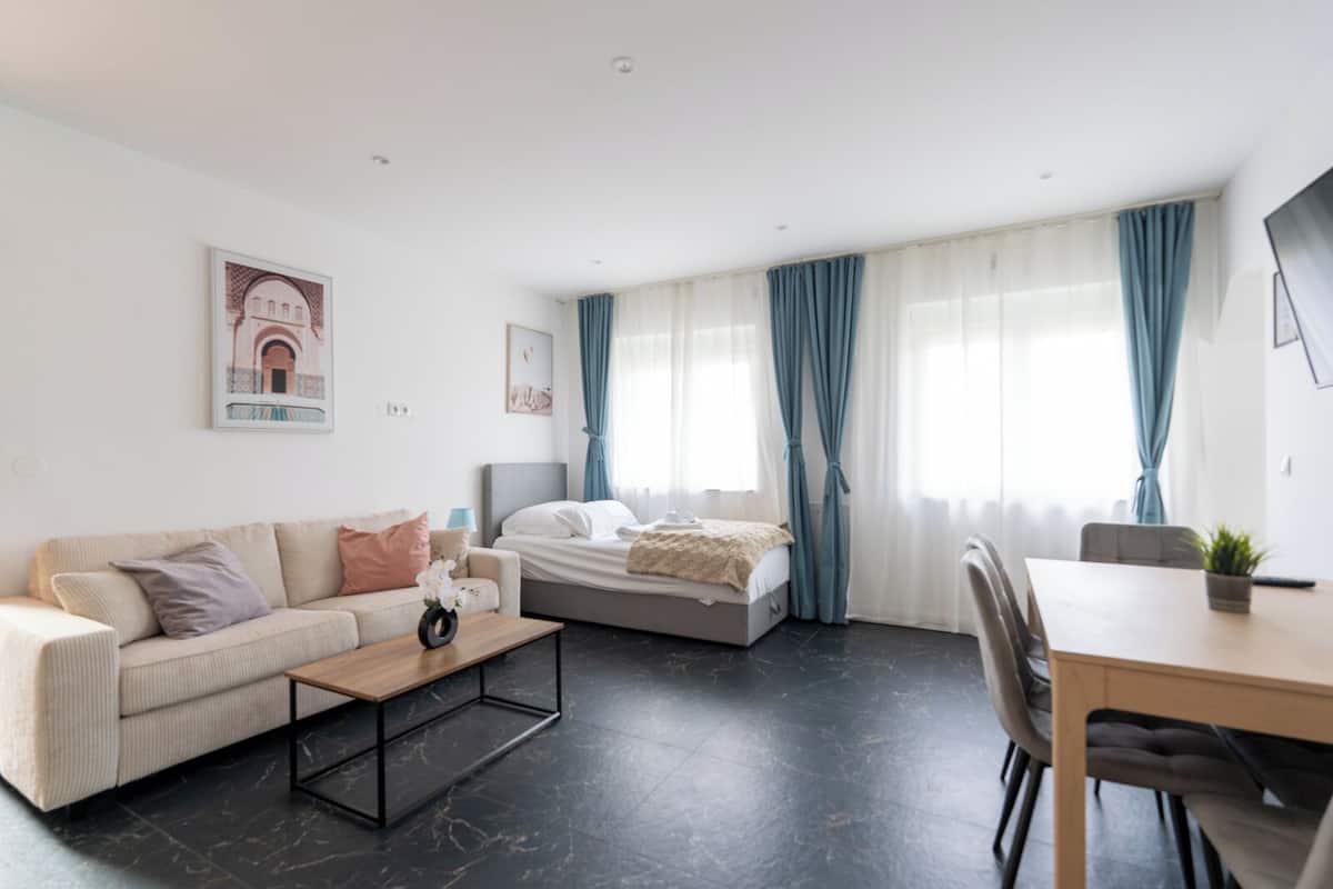 Ein modernes Wohnzimmer mit Sofa, Bett, Esstisch und Couchtisch.