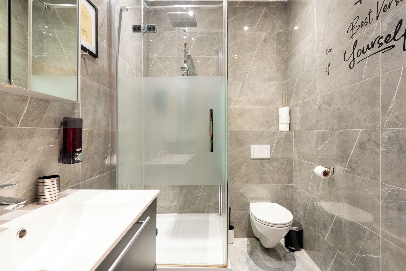 A modern bathroom with a glass shower enclosure, a white sink, and a toilet.