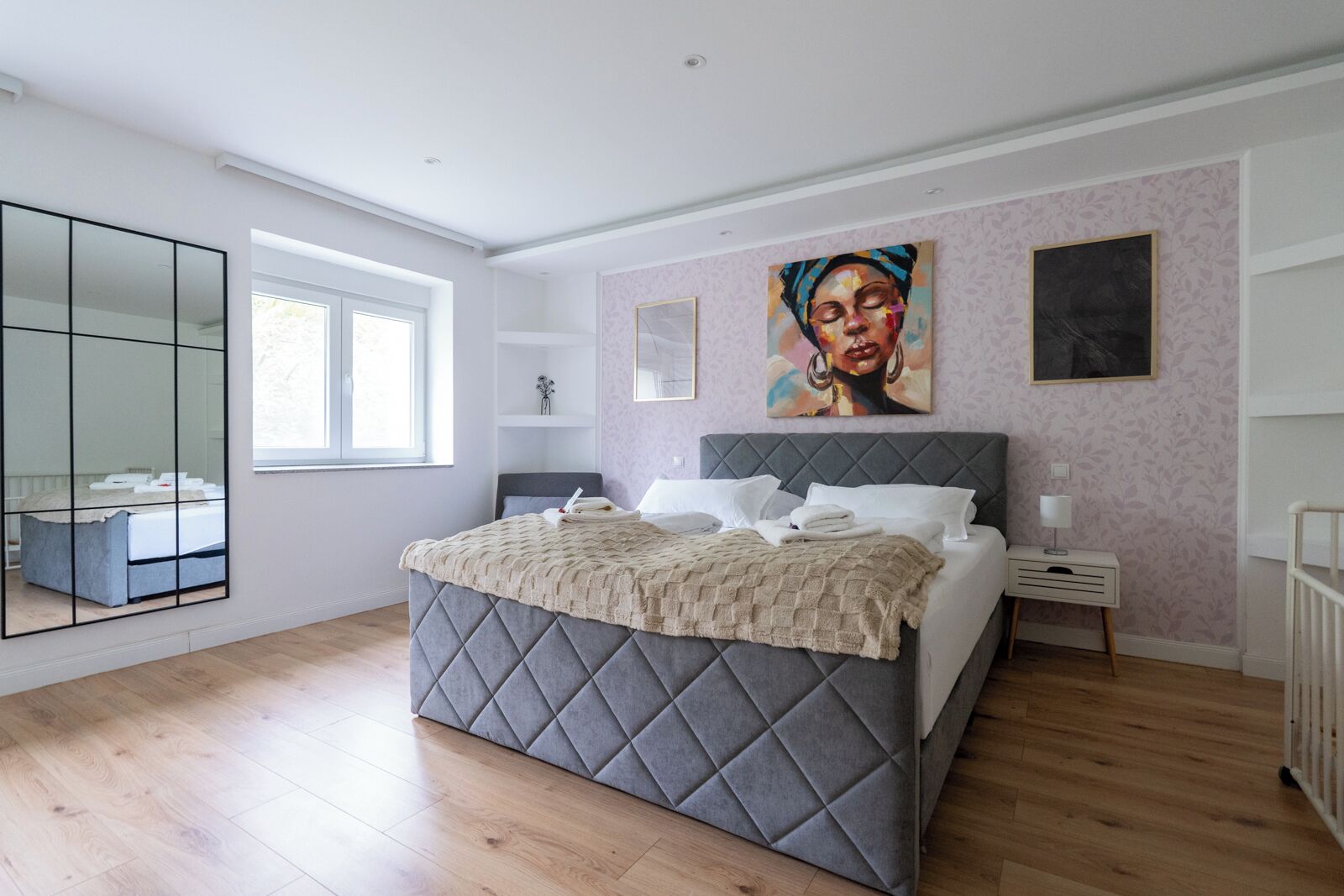 Un dormitorio con una cama grande, una mesita de noche, un espejo y cuadros en la pared.