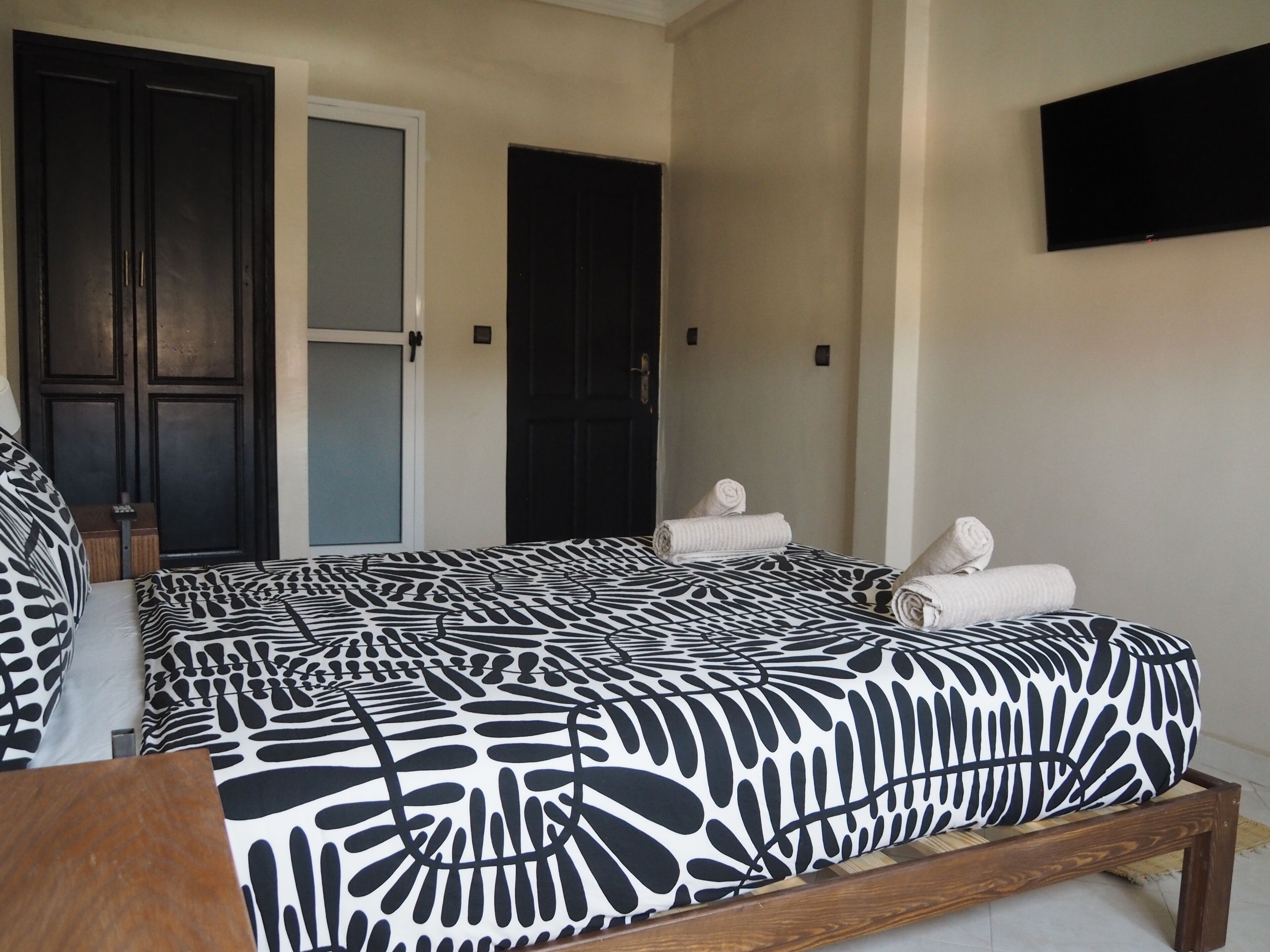 Une chambre à coucher avec un lit, deux portes et un téléviseur à écran plat fixé au mur.