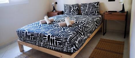 Un lit recouvert d’une couvre-lit à motifs zébrés, deux tables de chevet avec des lampes et une fenêtre avec des stores.