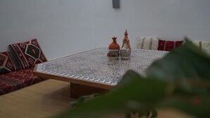 A room with a low wooden table, a patterned tablecloth, and two decorative vases. - Al Mohit Hotel Dakhla (Dakhla)