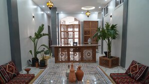 A lobby with a patterned floor, a reception desk, and two sofas with patterned cushions. - Al Mohit Hotel Dakhla (Dakhla)