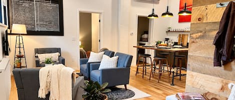 A modern living room with a sofa, a coffee table, and a dining area with a bar stool.