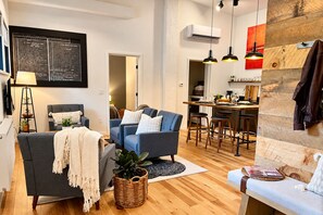 Un salon moderne avec un canapé, une table basse et un coin repas agrémenté d’un tabouret de bar.