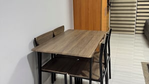 A dining area with a wooden table and chairs, a wooden cabinet, and a sliding door. - Studio Unit with Balcony in Manila (Manila)