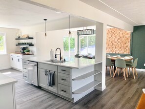 Una cucina moderna con una grande isola, elettrodomestici integrati e un'area pranzo caratterizzata da una parete in mattoni.
