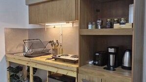 A compact kitchen with a wooden countertop, a built-in stove, a refrigerator, and a coffee maker.