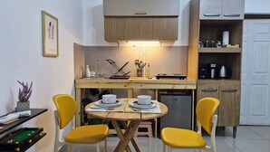 A compact kitchen with a dining table, two yellow chairs, a sink, and a coffee maker.