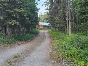 A gravel road leading to a cabin labeled 'HANNAH'S' surrounded by dense forest.