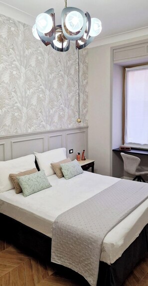 A bedroom with a bed, a nightstand, a chair, a window, and a ceiling light fixture. - LeChiavidiCasa (Roma)