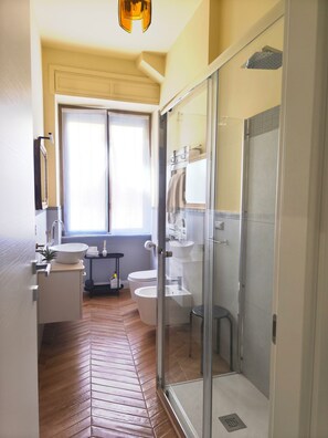 A bathroom with a glass-enclosed shower, a toilet, and a sink with a mirror above it. - LeChiavidiCasa (Roma)