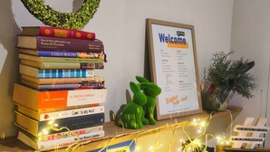 A stack of books, a welcome sign, a decorative bunny, and a blue cabinet with lights. - LeChiavidiCasa (Roma)