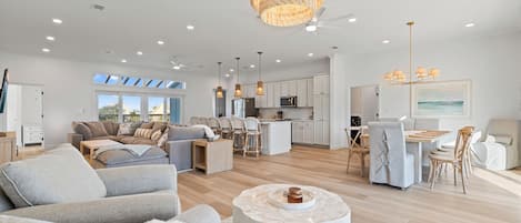 A spacious living area with a modern kitchen, dining area, and a large window providing natural light.