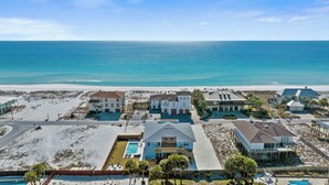 Zona residencial costera con varias casas, una piscina y una playa al fondo.