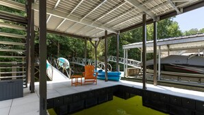 A covered outdoor swimming pool with a deck area, lounge chairs, and a boat. - Dockside Dreams-**Best Game/Movie Room at the Lake (Winchester)