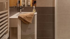 Un baño moderno con un espejo grande, un lavamanos, una toalla y una zona de ducha.