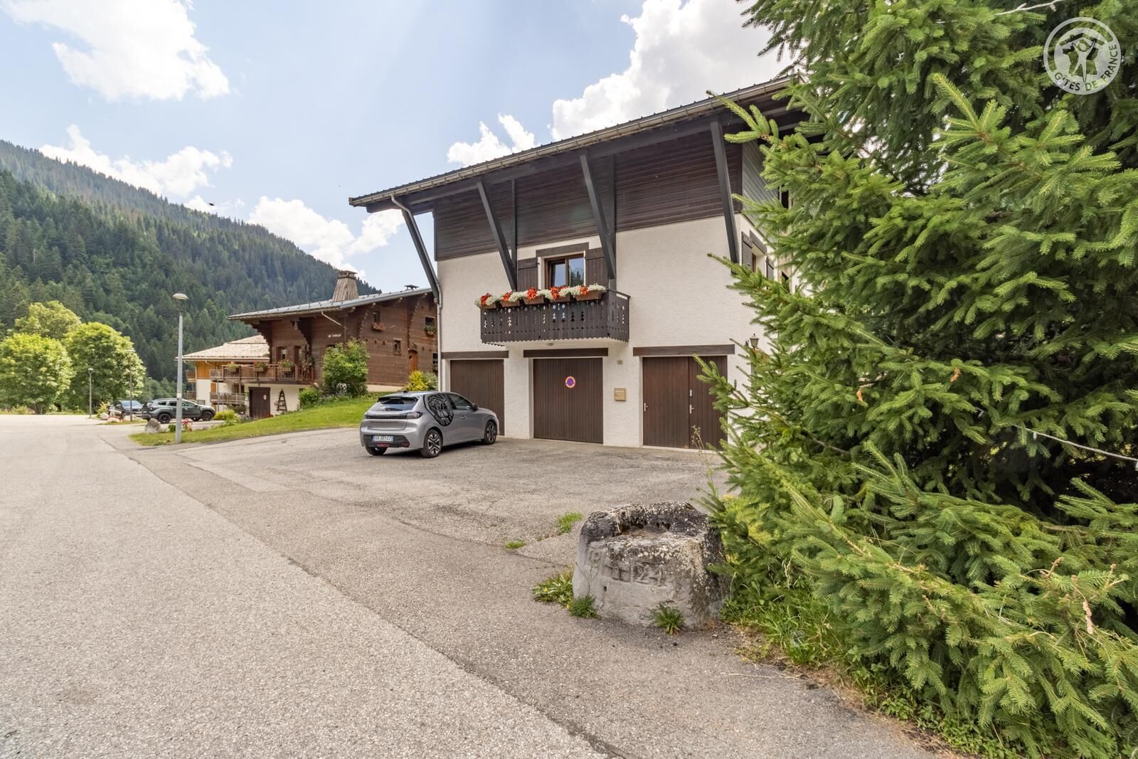 A two-story building with a balcony, a garage, and a parked car.