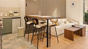 Une cuisine moderne avec un coin repas, comprenant un mur avec des lambris en bois, une table à manger avec des chaises et un canapé.