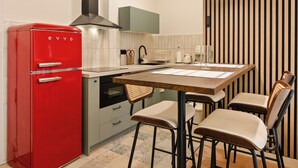Une cuisine de taille réduite avec un réfrigérateur rouge, une table à manger en bois et quatre chaises, et un mur à rayures.