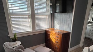 A room with a grey armchair, a wooden dresser, and a small table with a plant.