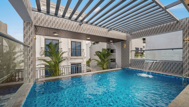 A swimming pool with a modern design, surrounded by a covered area with a pergola. - T P Villa (Da Nang)