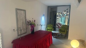 A room with a red table, a vase with flowers, and two green chairs. - Hôtel Les Pyramides Club  (Nabeul)