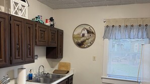 A kitchen with dark wooden cabinets, a white countertop, a sink, and a window with blinds. - Charming 2-bedroom apartment with WiFi, AC in Wabash. Great location (Wabash)