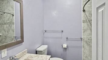 Een bad/douchecombinatie, handdoeken, zeep, shampoo