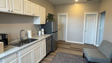 A modern kitchen with white cabinets, a stainless steel refrigerator, and a built-in dishwasher.