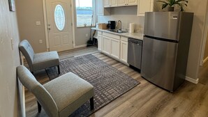 A modern kitchen with white cabinets, a stainless steel refrigerator, and a window with a view.