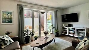 Un salon avec un canapé, une table basse, un téléviseur et une bibliothèque.
