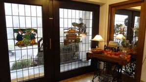 A room with a large wooden door with glass panels, a sewing machine on a table, and a lamp.
