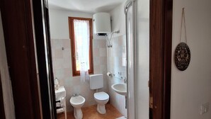 Un baño con inodoro, bidé, lavabo y ducha.