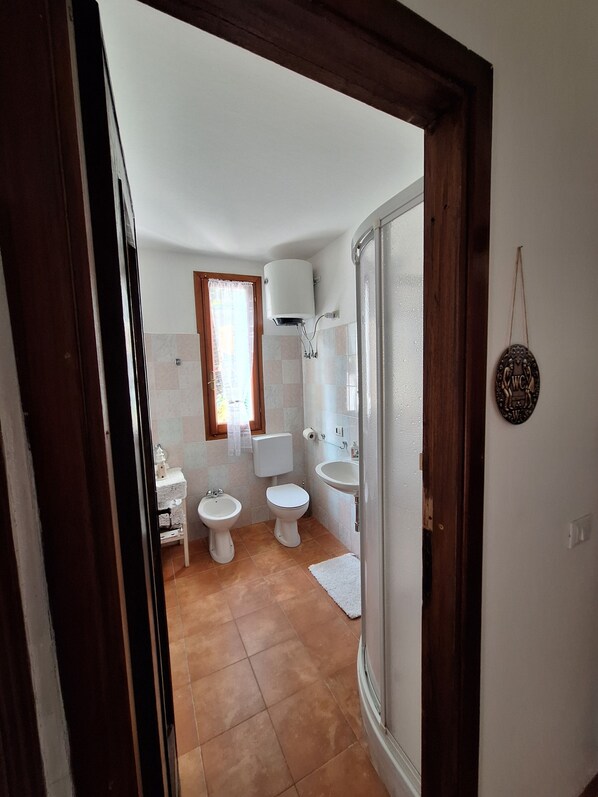 Un baño con inodoro, bidé, lavabo y ducha.