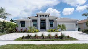 A modern two-story house with a front porch, a driveway, and landscaped garden. - WALK or BIKE to Beach, HEATED & PRIVATE pool & jacuzzi. NEWLY built & stunning. (Marco Island)