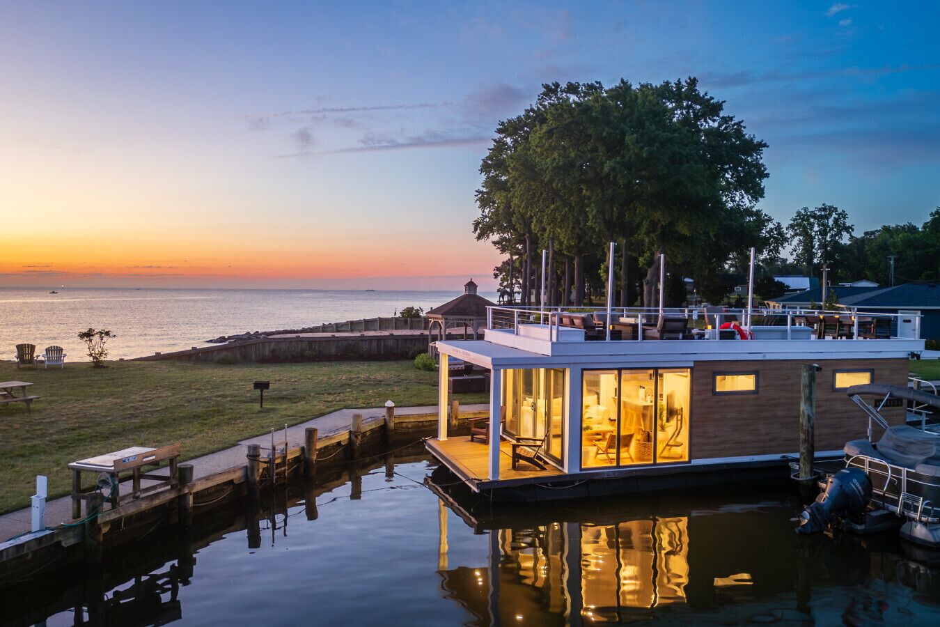 A waterfront house with a dock, a covered outdoor seating area, and a view of the water.